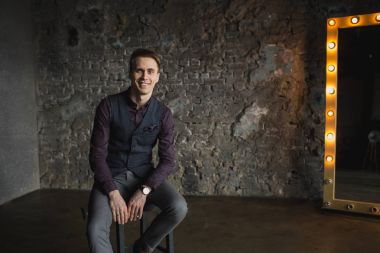 Mutlu gülümseyen yakışıklı adam kameraya gri arka plan üzerinde seyir siyah elbiseli