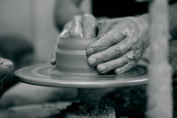 De handen van een pottenbakkers begeleiden met de keramische wiel — Stockfoto