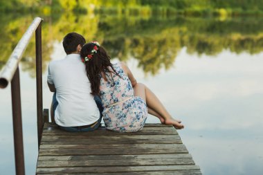 Bir iskelesi mavi bir bulutlu gökyüzü altında oturan bir adam ve kadın çift arkadan görünüm