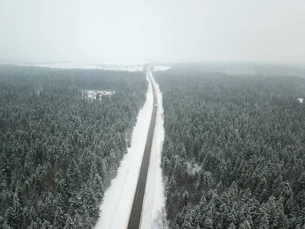 Winter road aerial view surrounded by snowy trees