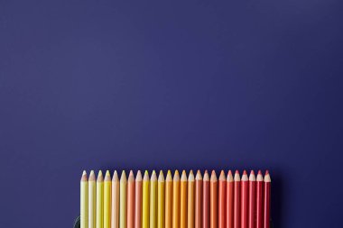 Mor bir arka plan üzerinde renkli kalemler. Güzel kompozisyon 