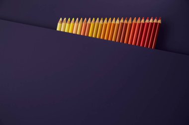 Mor bir arka plan üzerinde renkli kalemler. Güzel kompozisyon