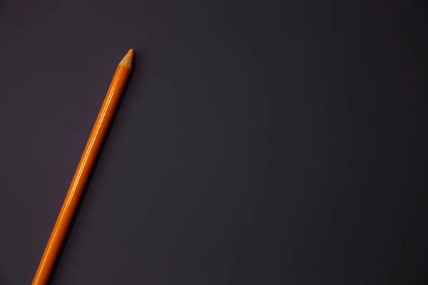 Um lápis laranja no fundo roxo . — Fotografia de Stock