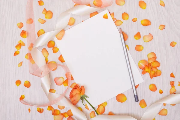 Una maqueta creativa con una tarjeta y una rosa de orang. Hoja vacía de pape — Foto de Stock