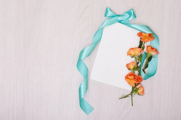 Una maqueta creativa con una tarjeta y una rosa de orang. Hoja vacía de pape — Foto de Stock