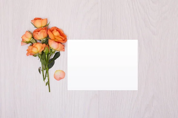 Una maqueta creativa con una tarjeta y una rosa de orang. Hoja vacía de pape — Foto de Stock