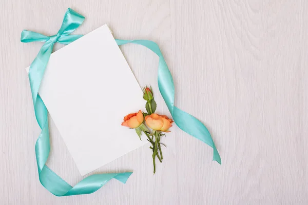 Una maqueta creativa con una tarjeta y una rosa de orang. Hoja vacía de pape — Foto de Stock