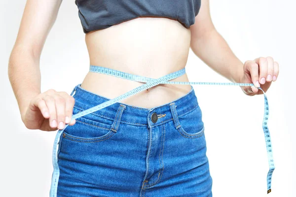 Slender girl measures her waist on a white background Stock Photo