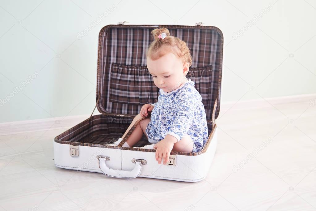 little girl is playing with a white suitcase