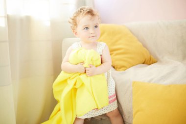 küçük çocuk odasında sarı battaniye ile oynuyor