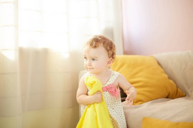 küçük çocuk odasında sarı battaniye ile oynuyor