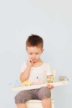 Küçük çocuk evde oyuncak arabayla oynuyor.