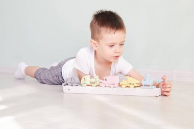 Küçük çocuk evde oyuncak arabayla oynuyor.