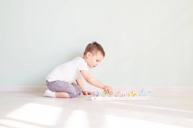 Küçük çocuk evde oyuncak arabayla oynuyor.