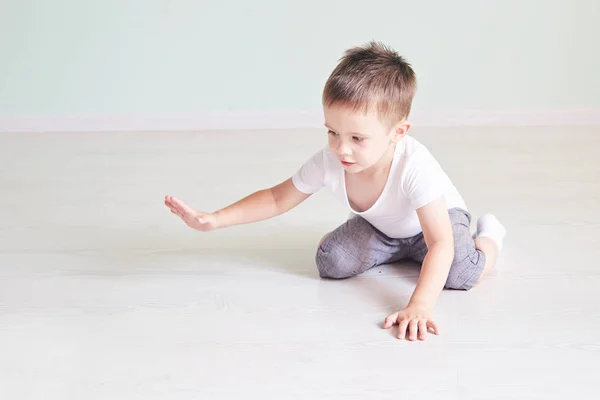 Quarto luminoso. Rapaz feliz a brincar no chão. Um rapaz de t-shirt branca — Fotografia de Stock