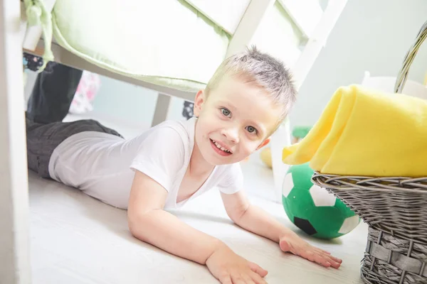 Little smiling boy is lying on a floor at home. — Stock Photo, Image