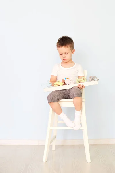 A boy plays with a machine and sits on the chair — Stock Photo, Image