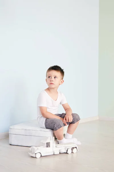 部屋の白いスーツケースに座っている少年 — ストック写真