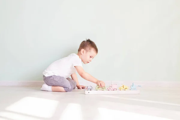 少年はおもちゃの車で家で遊んでいます — ストック写真