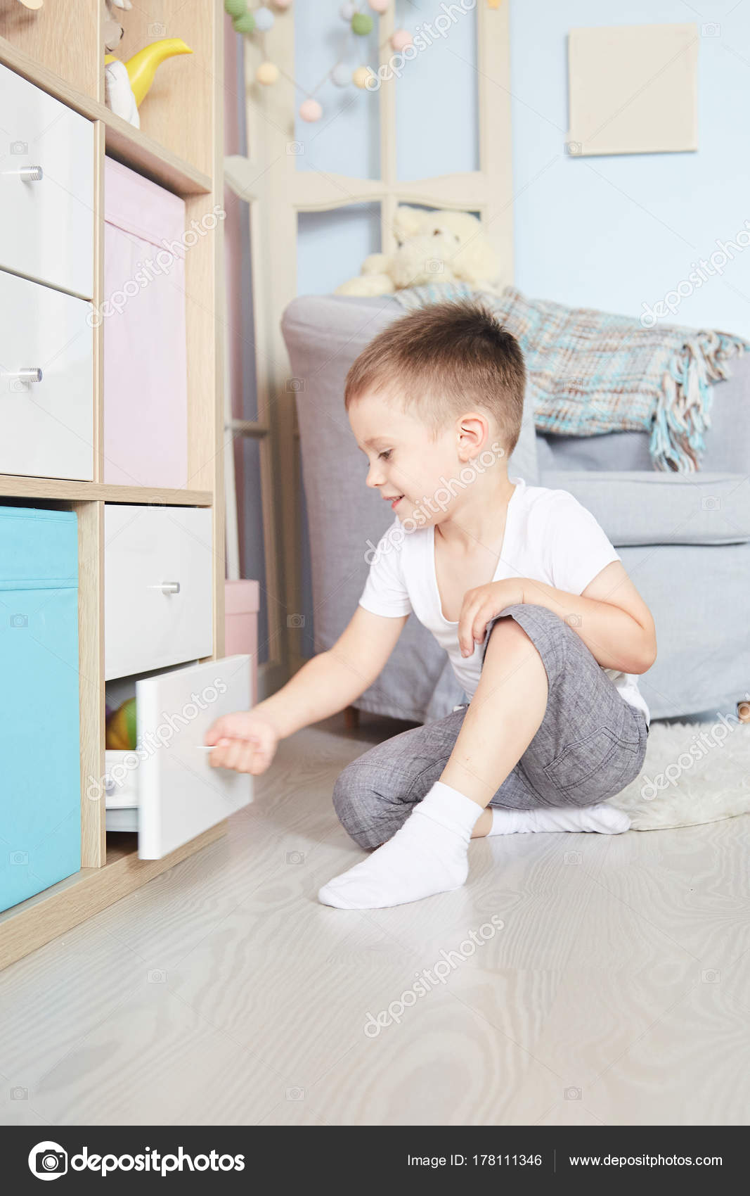 Boy In The Hands Sat On The Floor Near The Wardrobe Stock Photo