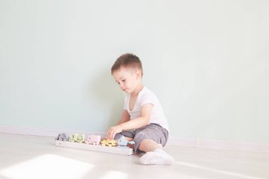 Küçük çocuk evde oyuncak arabayla oynuyor.