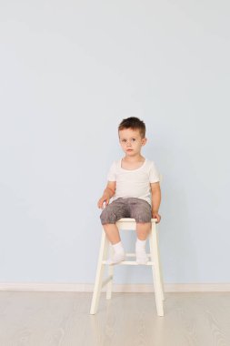 parlak oda. Çocuk Beyaz gömlekli bir yüksek sandalyede oturuyor