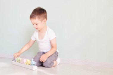 Küçük çocuk evde oyuncak arabayla oynuyor.