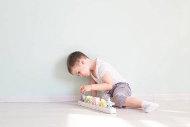 Küçük çocuk evde oyuncak arabayla oynuyor.