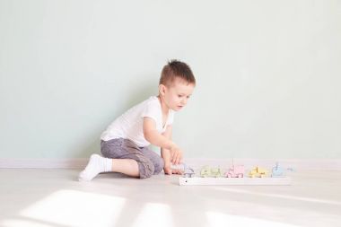 Küçük çocuk evde oyuncak arabayla oynuyor.