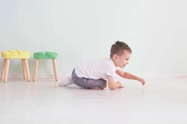 明るい部屋。床で遊んで幸せな少年。白い t シャツを着た少年 — ストック写真