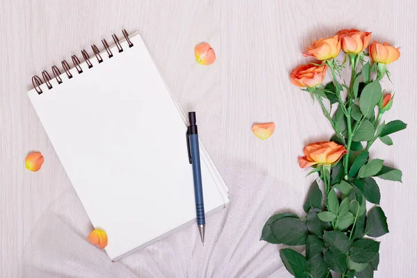 notebook paper, pen and dry flowers on background. white blank notebook and pencil and rose