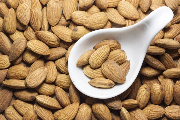 Almonds on a white background, or on a plain wooden table. Almonds in women's hands.