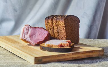 Çavdar unu ve pastırma bir kesme tahtası üzerinde bir parça ekmek