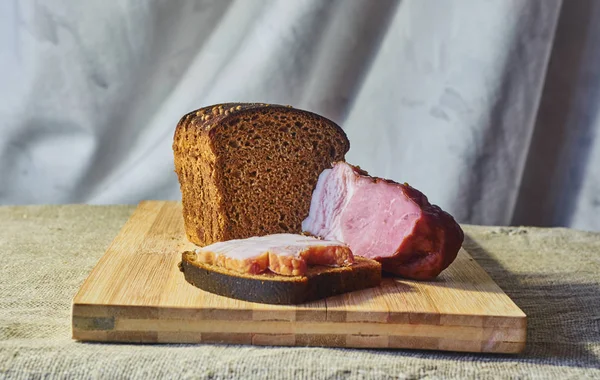 Çavdar unu ve pastırma bir kesme tahtası üzerinde bir parça ekmek