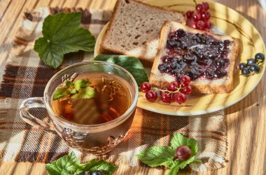 Bir tabak ve bir fincan çay nane, çilek tarafından çevrili ile reçelli sandviç.
