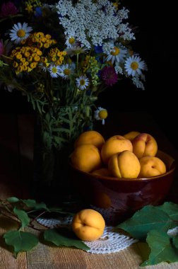 Kayısı ve kır çiçekleri ahşap kurullarında, düşük anahtar aydınlatma tekniği yürütülen bir buket ile natürmort