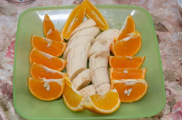 Orange slices and banana slices in a green plate