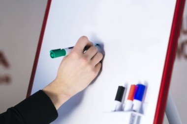 Bir adam, flipchart üzerinde yazıt siliyor. Beyaz arka plan flipchart. Bir adam siyah bir gömlek ve bir şık Gümüş Kol saati giymiş. Sünger panoları için. Beyaz tahta yazma mendil