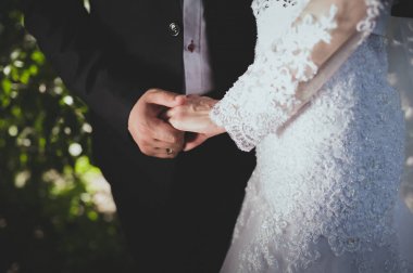 Siyah bir takım elbise ve el ele tutuşarak düğün elbise tasarımcısı gelin damat