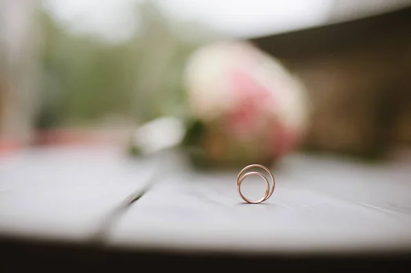 Свадебные кольца лежат на фоне букета цветов — стоковое фото