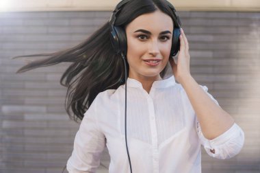  Çok güzel bir kız siyah büyük kulaklıklar gülümsüyor mutlu giyinmiş. Konu müzik dinliyor. Tablet