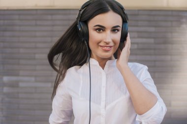  Çok güzel bir kız siyah büyük kulaklıklar gülümsüyor mutlu giyinmiş. Konu müzik