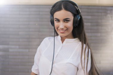  Çok güzel bir kız siyah büyük kulaklıklar gülümsüyor mutlu giyinmiş. Konu müzik