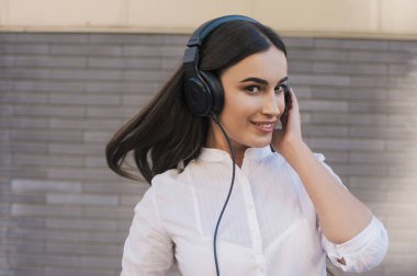  Çok güzel bir kız siyah büyük kulaklıklar gülümsüyor mutlu giyinmiş. Konu müzik