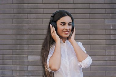  Çok güzel bir kız siyah büyük kulaklıklar gülümsüyor mutlu giyinmiş. Konu müzik