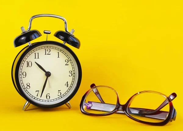 Klasik masa saati, beyaz bir arka plan üzerinde gözlük. 