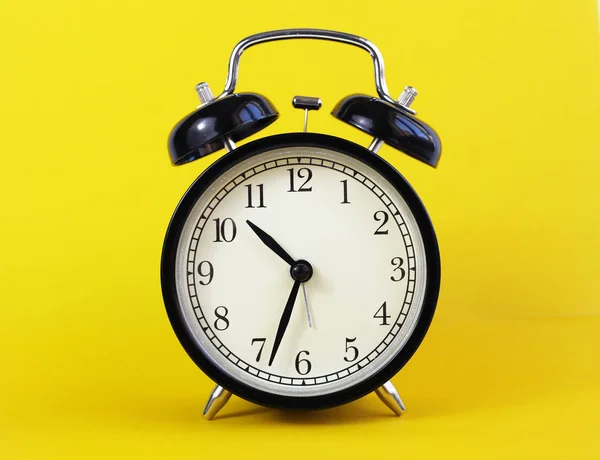 Reloj de mesa clásico sobre fondo amarillo. — Foto de Stock