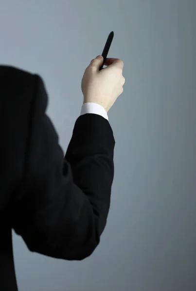 Mano de negocios apuntando sobre un fondo gris. Una pluma — Foto de Stock