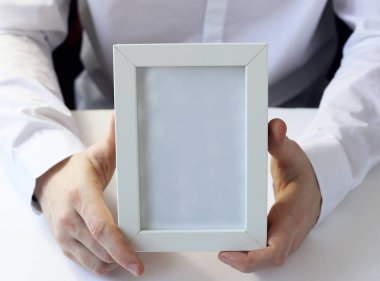 Elinde beyaz fotoğraf çerçevesi.