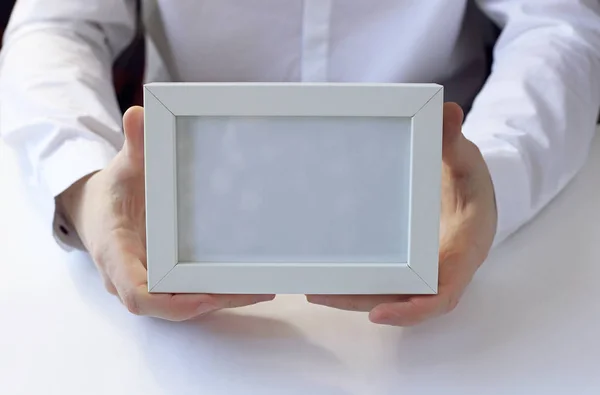 Elinde beyaz fotoğraf çerçevesi.